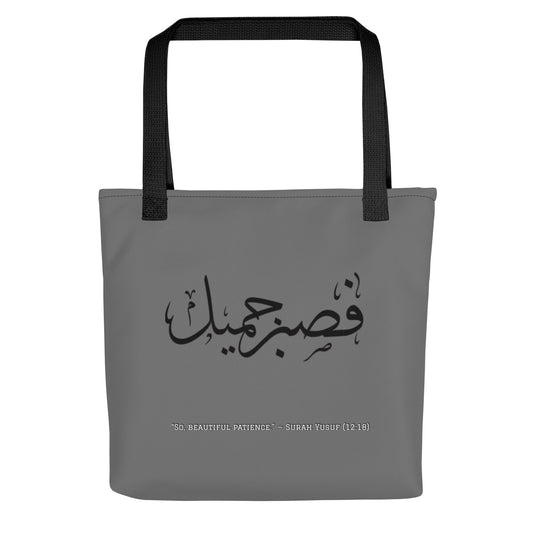 Gray tote bag with black handles and Arabic text on a white background